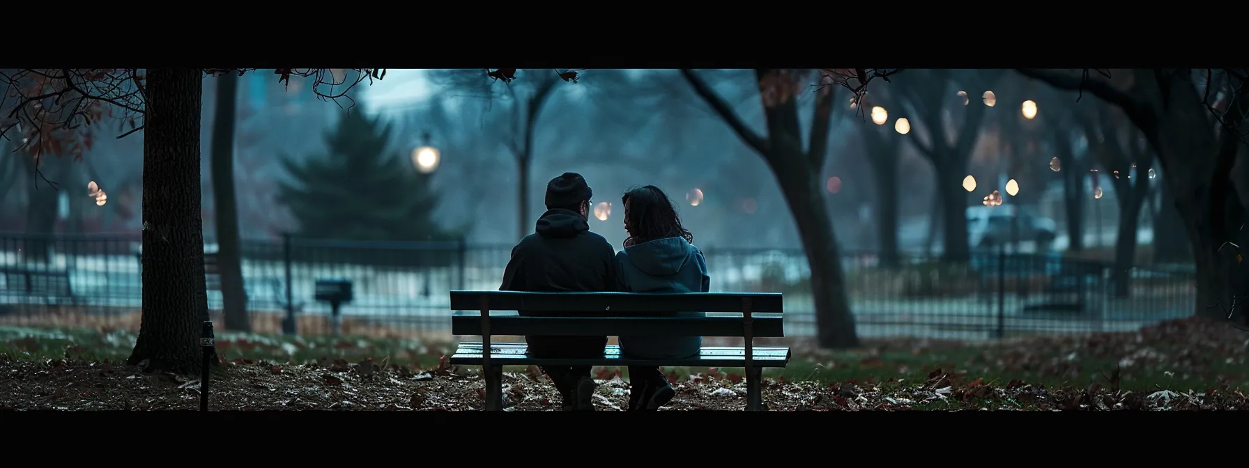 a couple sitting on a bench in a park, looking distant and somber as they try to navigate the impact of mental illness on their relationship.