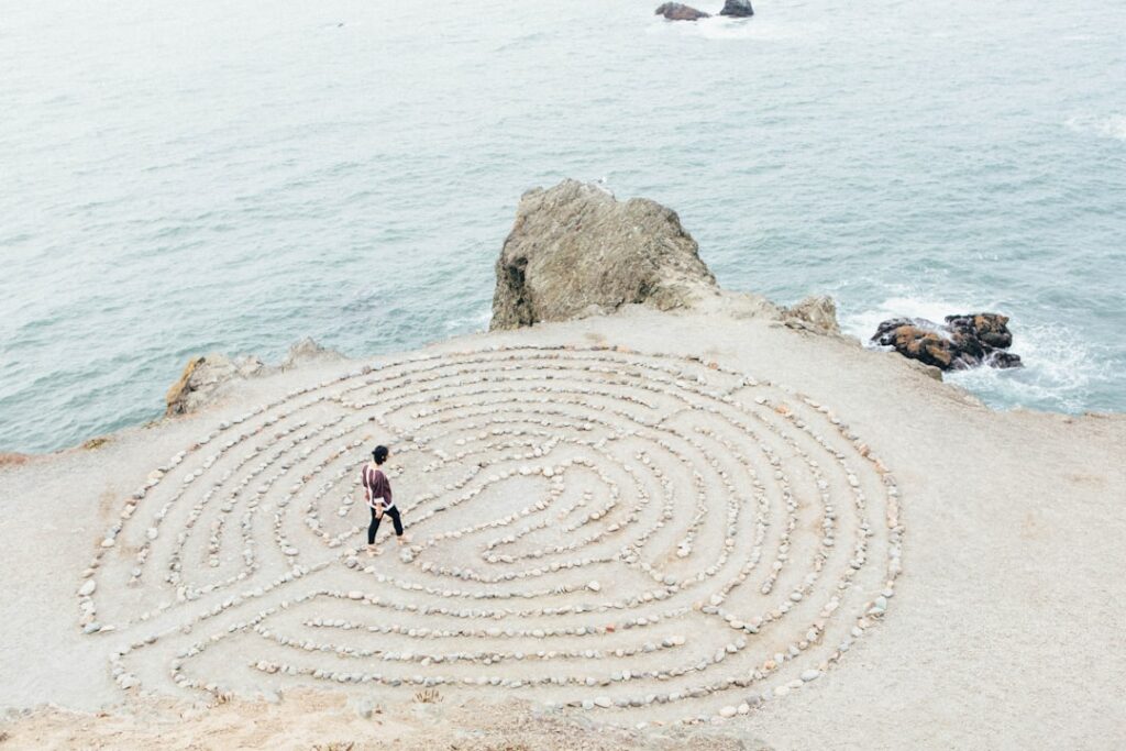 Mental health, behavioral health, Person walking in a seaside labyrinth, symbolizing a therapeutic journey.