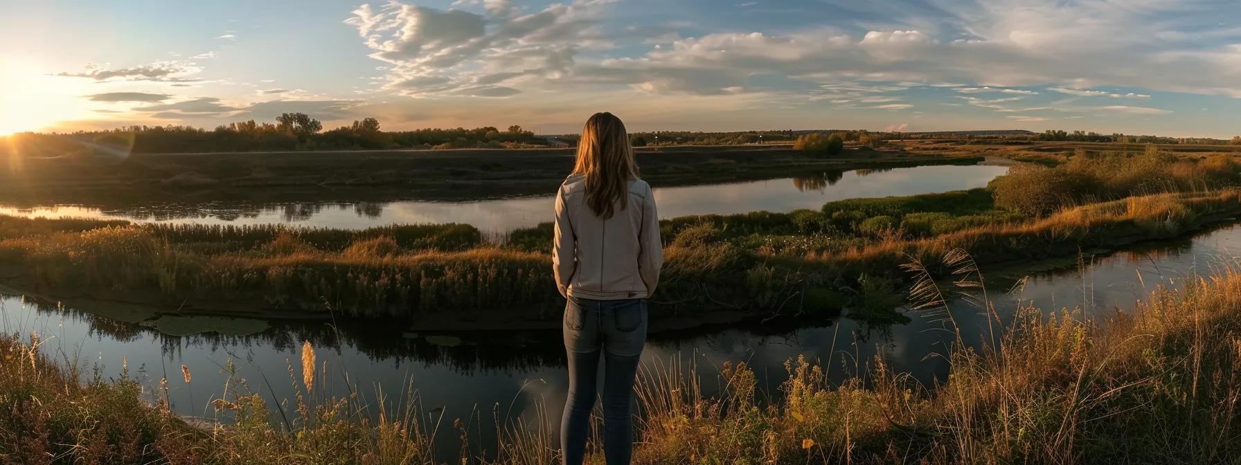 a serene, introspective woman stands gazing out at a tranquil landscape during golden hour, embodying resilience and the complexity of navigating bipolar disorder amidst societal pressures and hormonal influences.