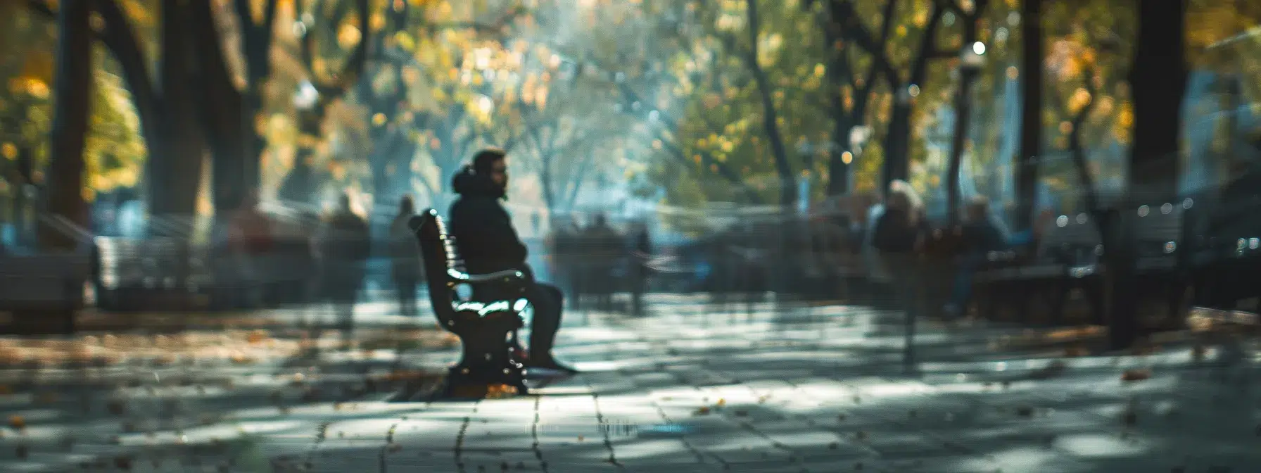 a somber figure sits alone on a park bench, surrounded by a blurred crowd, conveying the isolating grip of anxiety amidst the hustle and bustle of life.